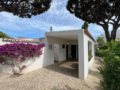 a white house with purple flowers in a courtyard at Traditional 3 bedroom villa with great pool in the heart of Vale do Lobo in Vale do Lobo
