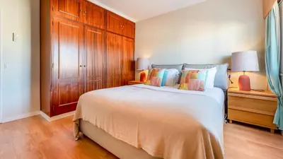 a bedroom with a large bed and wooden cabinets at Design Top Floor With Balcony & Pool in Vilamoura