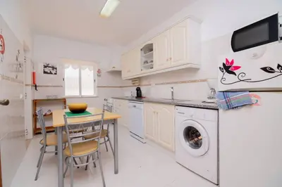a kitchen with a table and a washing machine at Galé Magda by Innkeeper in Guia
