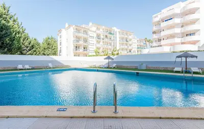 a swimming pool with an umbrella and some buildings at Apartamento em Albufeira - Condomínio com Piscina in Albufeira