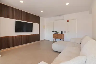 a living room with a couch and a tv on a wall at Apartamento em Albufeira - Condomínio com Piscina in Albufeira