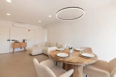 a living room with a wooden table and chairs at Apartamento em Albufeira - Condomínio com Piscina in Albufeira