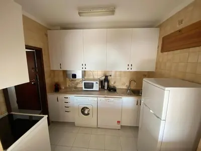 a kitchen with white cabinets and a white refrigerator at Quarteira-Mar in Quarteira