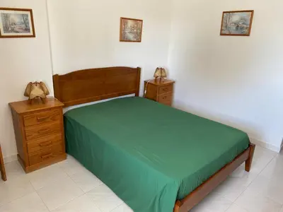 a bedroom with a bed with a green bedspread and two night stands at Quarteira-Mar in Quarteira