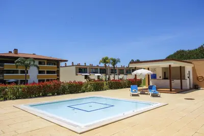 a swimming pool with two chairs and a building at Central Algarve Duplex Retreat with Garden & Pool in Quarteira
