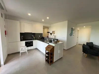 a large kitchen with white cabinets and a table at Gardens Dubai by FHR in Vilamoura
