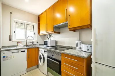 a kitchen with wooden cabinets and white appliances at BeGuest Summer Breeze in Vale Parra in Galé