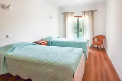a bedroom with two beds and a chair at Villa ENCOSTA VISTA SALGADOS - BY BEDZY in Guia