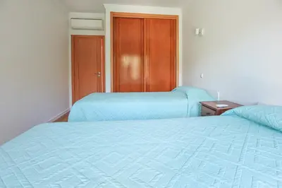 a bedroom with two beds and a wooden cabinet at Villa ENCOSTA VISTA SALGADOS - BY BEDZY in Guia