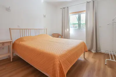 a bedroom with a bed with an orange comforter at Villa ENCOSTA VISTA SALGADOS - BY BEDZY in Guia