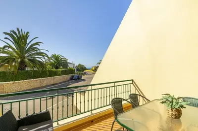 a balcony with a table and chairs and a street at Rosal Beach House in Albufeira