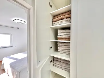 a room with white walls and a closet filled with towels at Holiday Apartment Albufeira in Albufeira