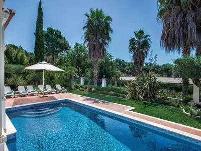 a swimming pool with chairs and an umbrella at Exquisite Quinta Da Lago Villa Villa Majestic Heights 4 Bedrooms in Almancil