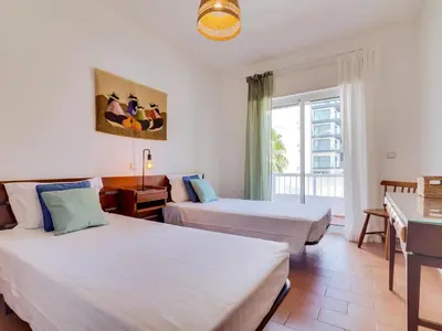 a hotel room with two beds and a window at AL - Apartamento Maré Baixa in Quarteira