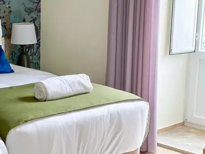 a white towel sitting on the end of a bed at Guest House Jacarandá Faro in Faro