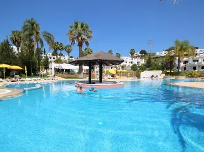 a large swimming pool with a person in the water at The Sun - Clube Albufeira Garden Village in Albufeira