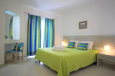 a bedroom with a green bed with a desk and windows at The Sun - Clube Albufeira Garden Village in Albufeira