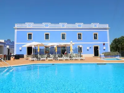 a blue building with a swimming pool in front of it at The Sun - Clube Albufeira Garden Village in Albufeira