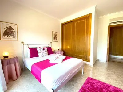 a bedroom with a large white bed with pink sheets at Vilamoura Typical 2 With Pool by Homing in Vilamoura