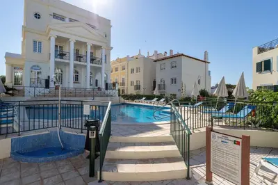 a swimming pool in front of a building at Charming triplex T2 in the Old Village Vilamoura in Quarteira
