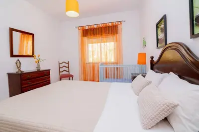 a bedroom with a large white bed and a crib at Casinha I by Innkeeper in Guia
