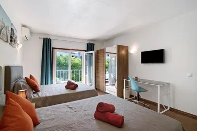 a hotel room with two beds and a desk and a television at Hanna's Sunny Apartment in Albufeira