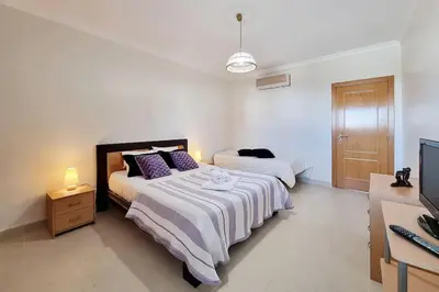 a white bedroom with two beds and a television at Sea Beside in Albufeira