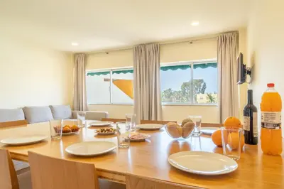 a dining room with a wooden table with plates and glasses at Mourabel Apartment - S by HelloVacations in Loulé