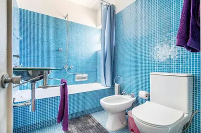 a blue tiled bathroom with a toilet and a shower at Sunny Villa with golf front view in Vilamoura
