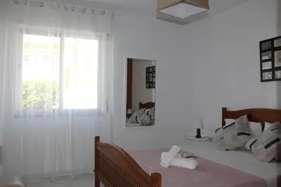 a white bedroom with a bed with a window at Casa do Limoeiro in Albufeira