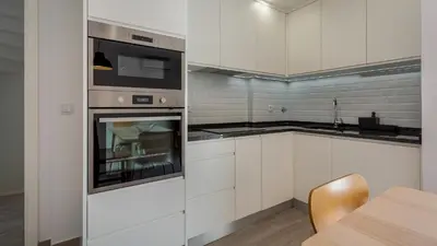 a kitchen with white cabinets and a stainless steel oven at 2 BDR Vilamoura Escape W Balcony by LovelyStay in Quarteira