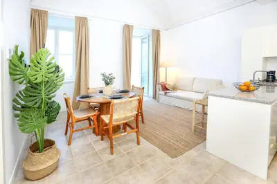 a kitchen and living room with a table and a couch at Doce Faro Niente Apartment in Faro