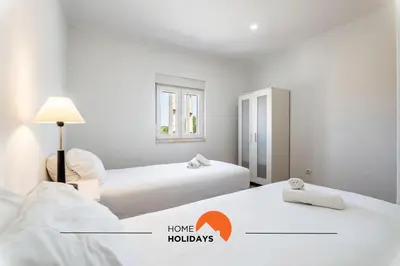two beds in a white room with a sign that says home holidays at #179 Monte das Churras 2 by Home Holidays in Albufeira