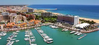 a beach with chairs and umbrellas and the ocean at T2 Vila Atlântida Praia Vilamoura in Quarteira