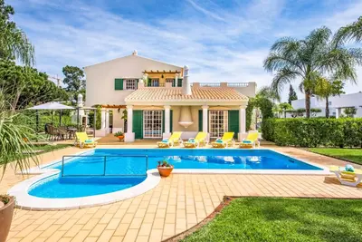 a villa with a swimming pool in front of a house at Villa Vargues in Quarteira