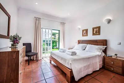 a bedroom with a bed and a desk and a window at Villa Vargues in Quarteira