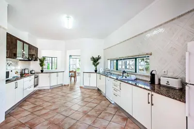 a large kitchen with white cabinets and a tile floor at Villa Luis in Galé