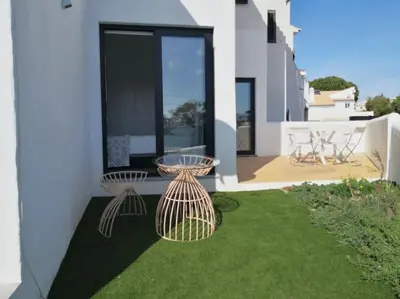 a patio with two tables on the grass at Airy 3br, AC, Garden, 2min Strip, 8min Oura Beach in Albufeira