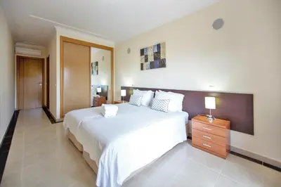 a bedroom with a large white bed and a wooden dresser at Villa Albufeira by Atlantic Places in Albufeira