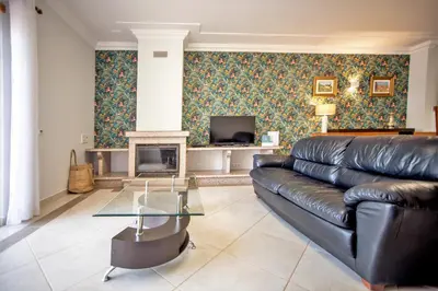 a living room with a leather couch and a fireplace at Villa Albufeira by Atlantic Places in Albufeira