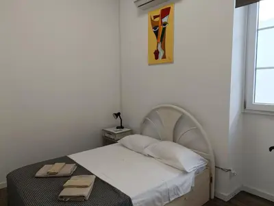 a small white bedroom with a bed and a window at Albergaria Formosa in Faro