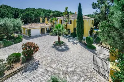 a yellow house with a gate and a courtyard at Villa Plaza - beautiful spacious house off roundabout 6 Quinta Do Lago in Quinta do Lago