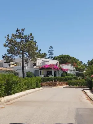 a road leading to a white house with pink flowers at Albufeira - Casa Balaia Resort in Albufeira