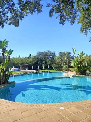 a swimming pool with blue water and trees in the background at Albufeira - Casa Balaia Resort in Albufeira