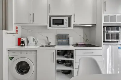 a kitchen with a washing machine and a microwave at Estudio Balaia by Villas Key in Albufeira