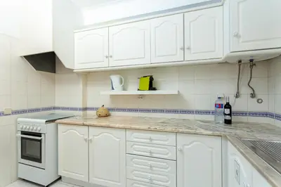a white kitchen with white cabinets and a counter top at Host Wise - Fresh Sunny Flat with Pool & Terrace in Olhos de Água