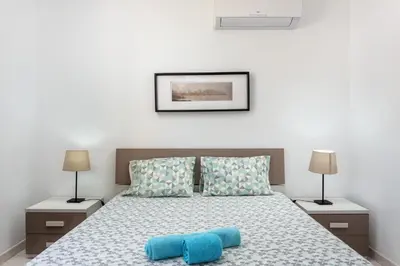 a bedroom with a bed with two blue pillows at Host Wise - Fresh Sunny Flat with Pool & Terrace in Olhos de Água