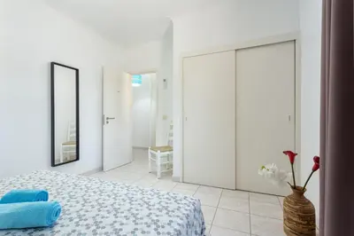 a white bedroom with a bed and a vase with flowers at Host Wise - Fresh Sunny Flat with Pool & Terrace in Olhos de Água