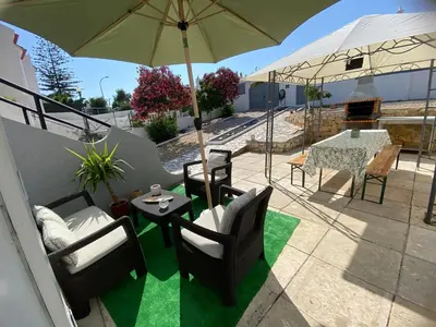 a patio with chairs and a table with an umbrella at Moradia Olival- BBQ, 2 Quartos, Quintal in Albufeira