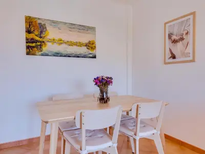 a dining room table with white chairs and a vase of flowers at AL - Apartamento Quinta do Romão in Quarteira